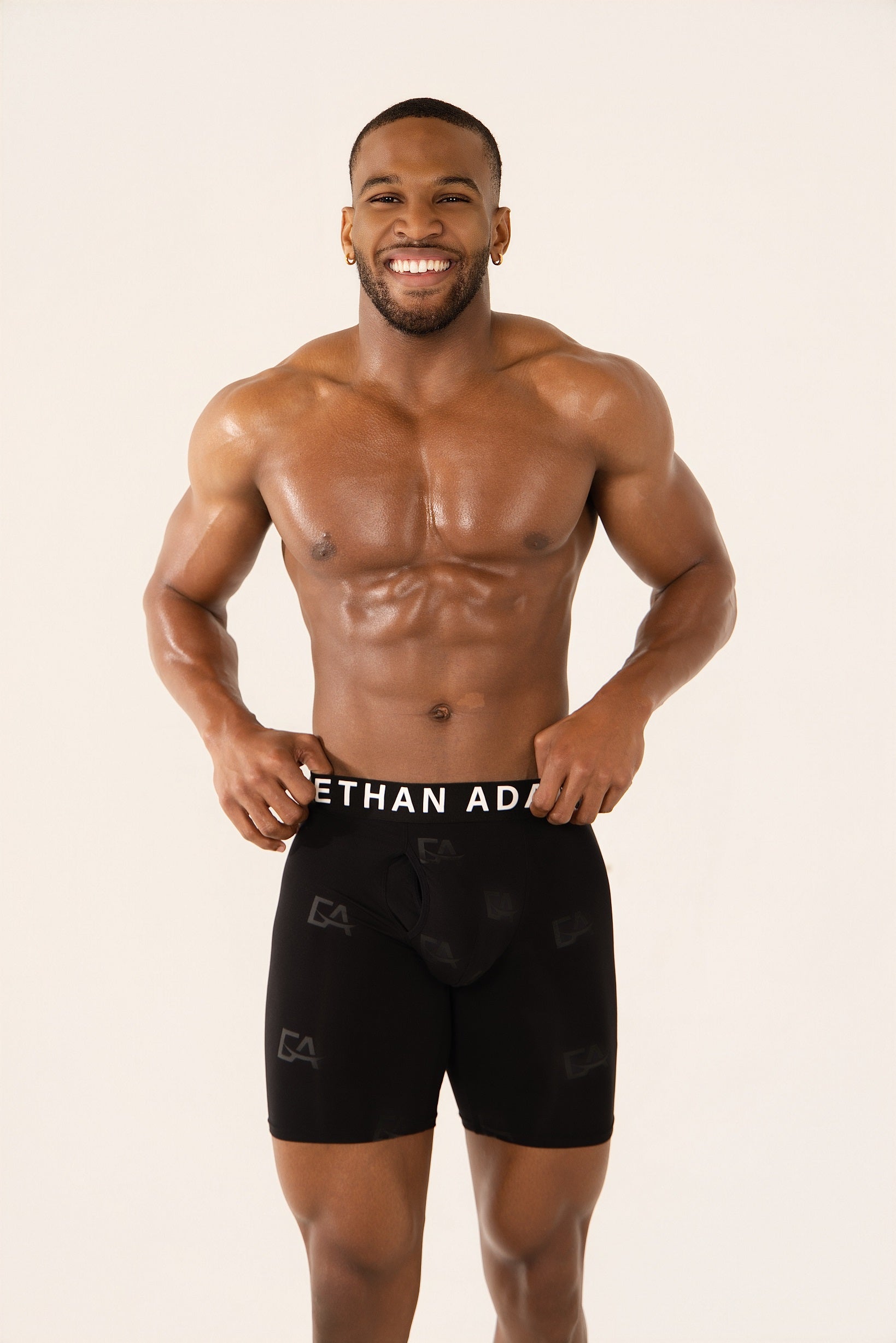 Man wearing black athletic shorts with a visible brand logo on a beige background